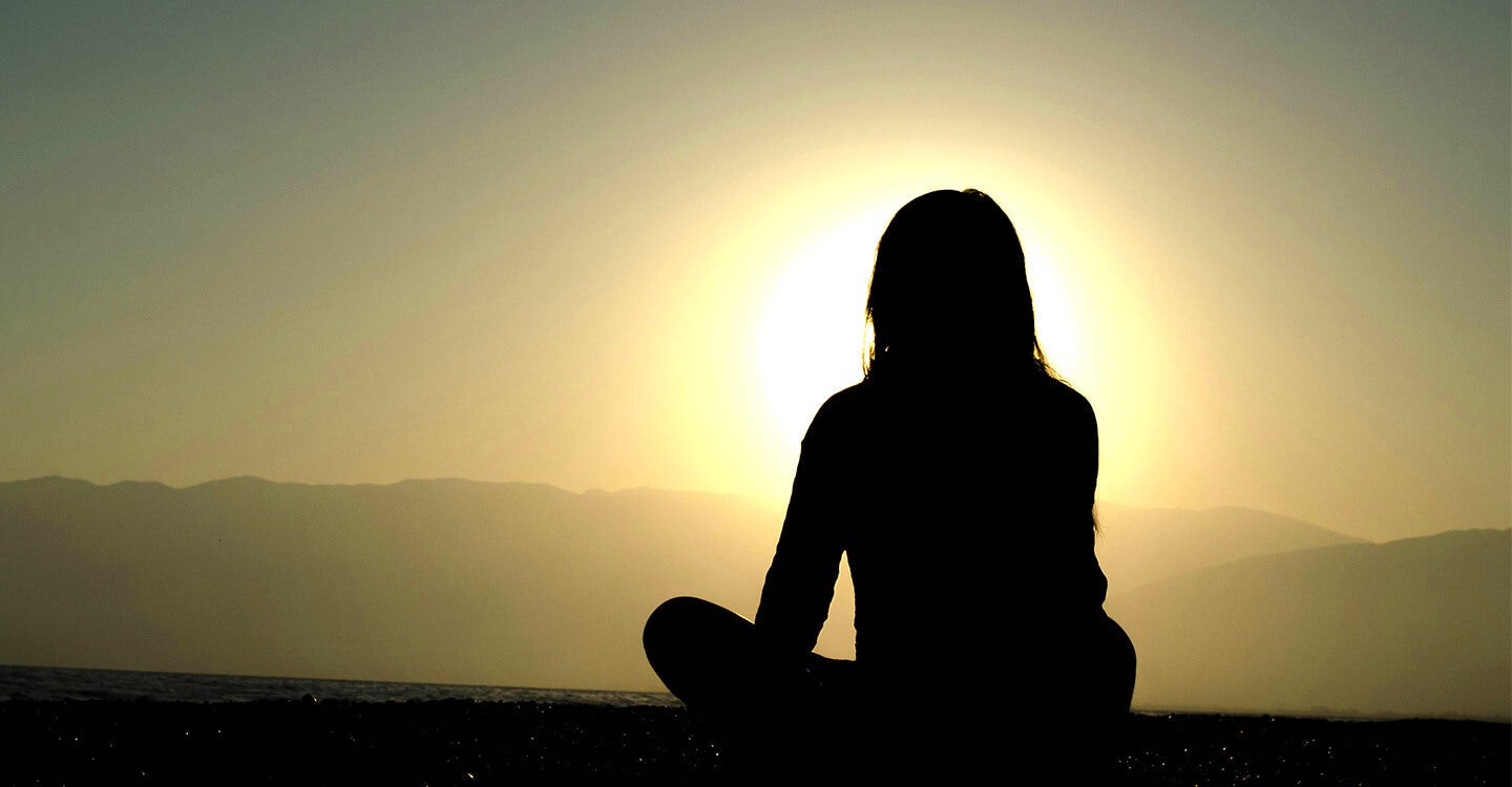 Meditating in the early morning with sunrise light breaking over the horizon, symbolizing the spiritual benefits of Shilajit and inner calm, focus, and energy balance.